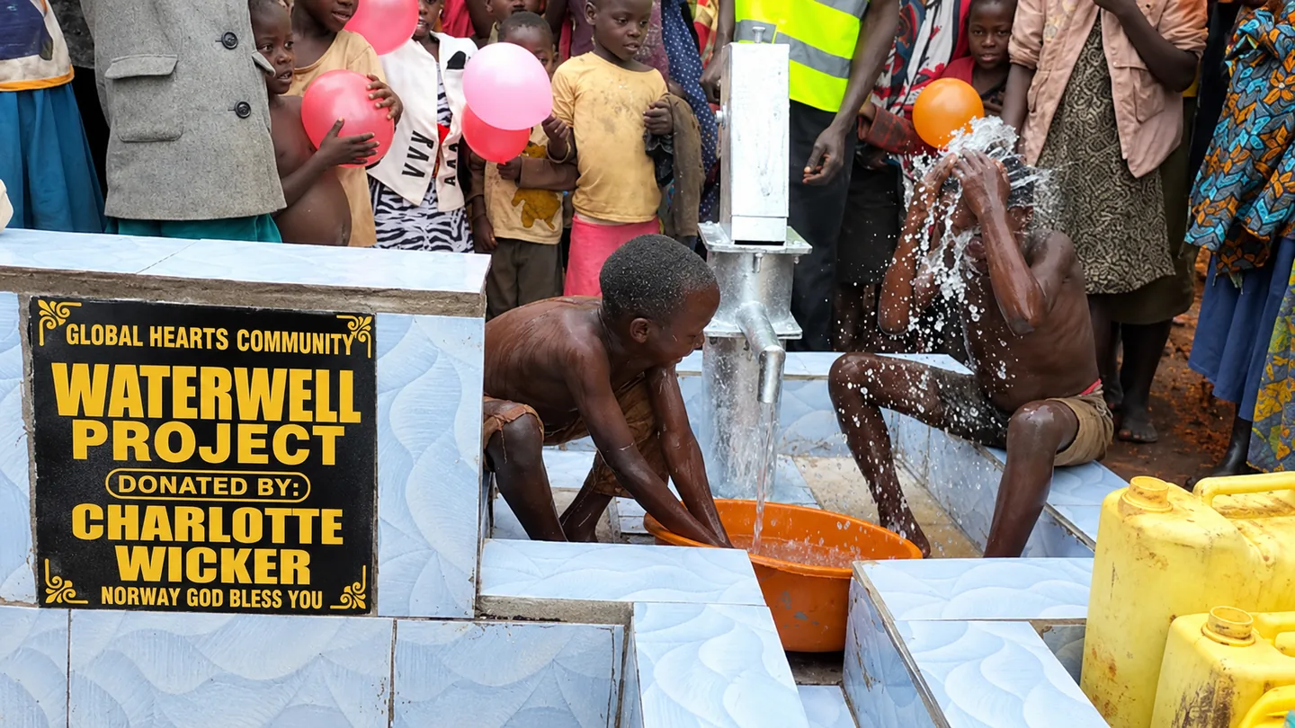 Children and community members celebrate a Global Hearts Community water well in Mbale, Uganda.